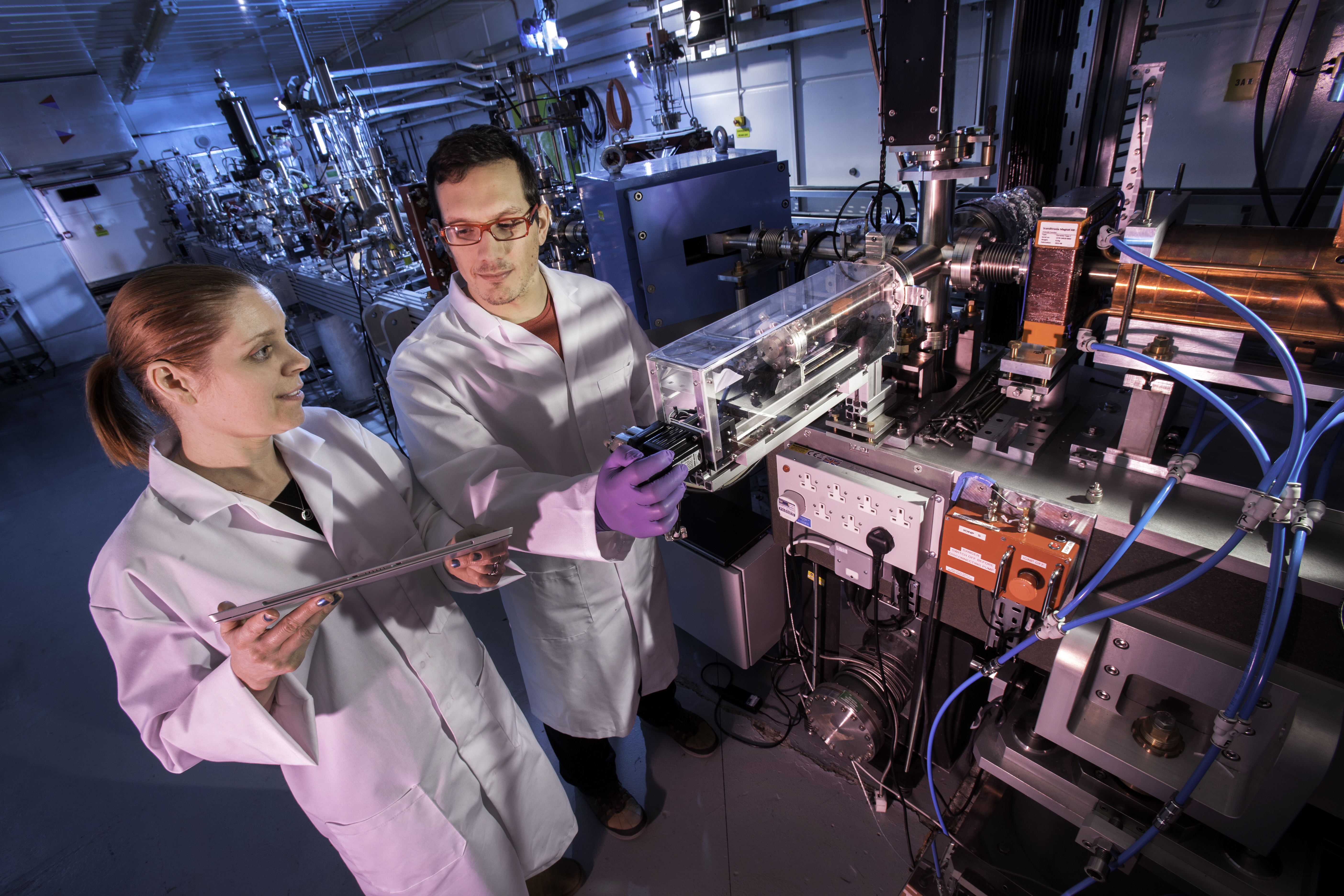 Two people stood alongside a particle accelerator